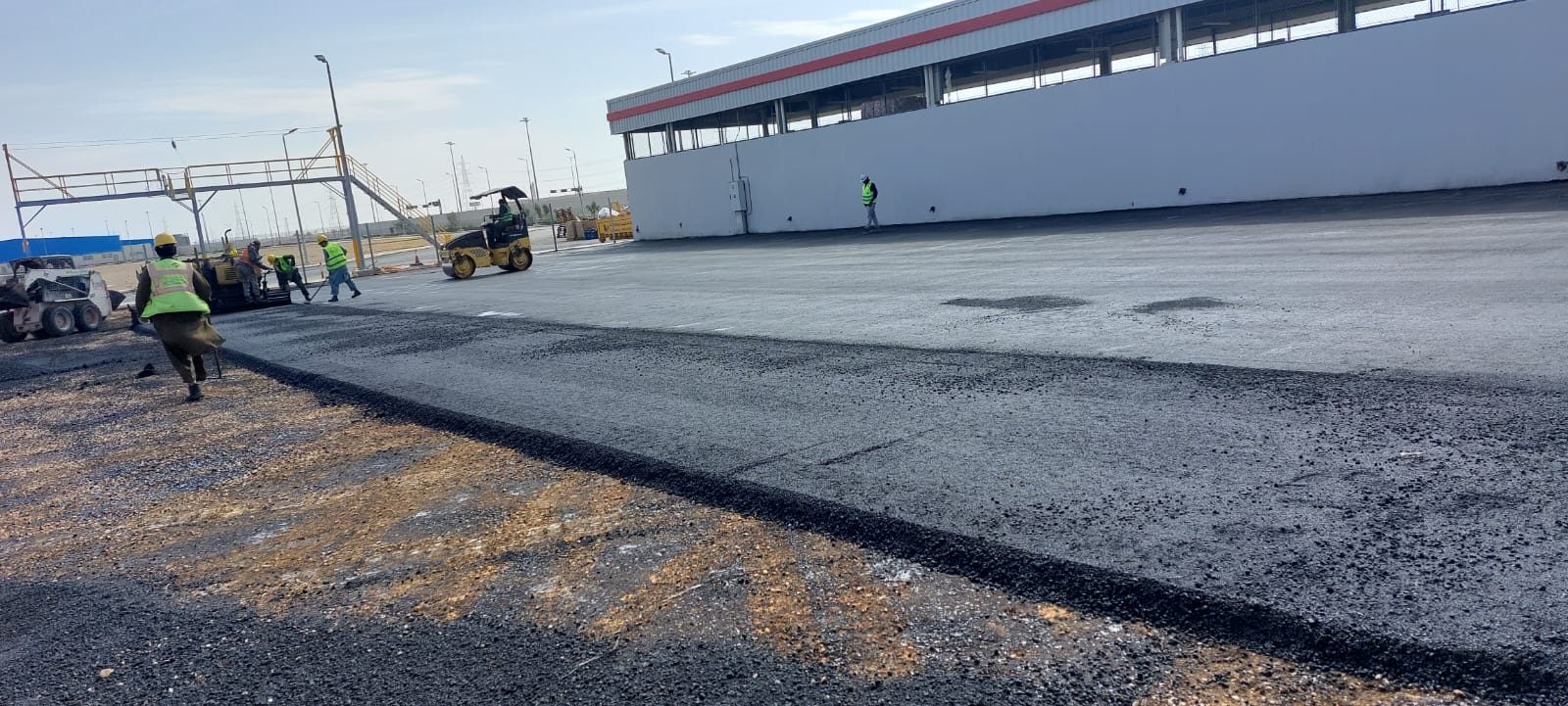 Freshly laid and rolled asphalt wearing course alongside a warehouse yard
